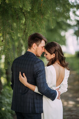A man and woman kissing outdoors. They are dressed in wedding attire, suggesting a romantic or wedding-related