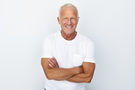 Portrait of happy senior man with arms crossed standing against grey background