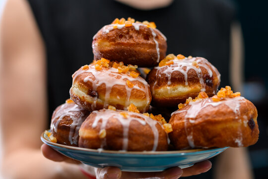 Domowe pączki z lukrem i sk&oacute;rką pomarańczową sterta na talerzu