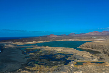 Fototapeta premium Drone panoramic view of Playa del Janubio in Lanzarote with the volcanic landscape in the background with turquoise sea and big waves. Nature and tourism. Canary Islands, Spain.