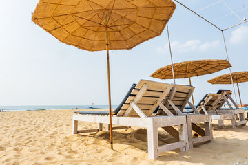 colorful wooden beach umbrellas and sunbeds loungers on sandy beach of ocean