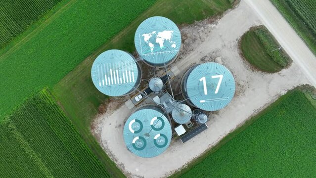 Grain silos with digital overlays for IOT and autonomous unloading in precision agriculture. Top down spinning aerial drone shot with special effects animation. Global agronomy theme.