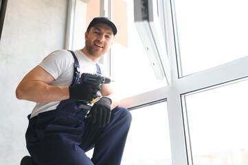 handsome young man installing bay window in new house construction site