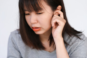 Woman has itchy ears, It can happen for many reasons. Both using headphones chemical allergy or it could be a sign of infection.