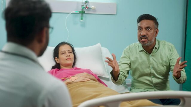 Shoulder shot, angry patient husband scolding or arguing with doctor at hospital ward - concept of emergency, communication problems and dispute