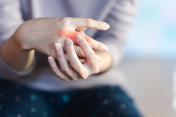 A woman touches a red area on her finger to indicate the pain point.