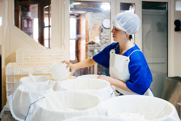 Female worker making cottage cheese at factory