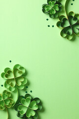 St Patricks Day frame made of paper cut clover and confetti on green background.