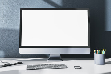 Modern designer office desktop with empty white mock up computer monitor, supplies and other items on gray wall background. 3D Rendering.