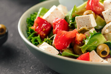 Portion of fresh greek salad on grey background