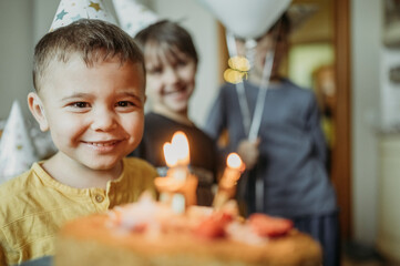 Happy boy with birthday cake and siblings in background