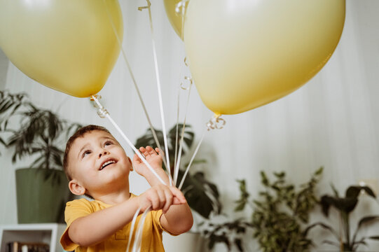 Happy boy playing with balloons at home
