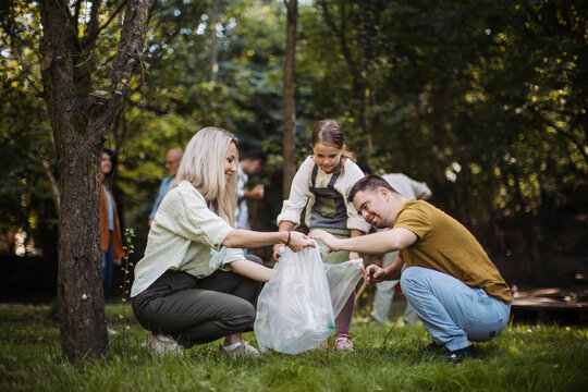 Socially inclusive group of volunteers collecting plastic waste in public park - Powered by Adobe