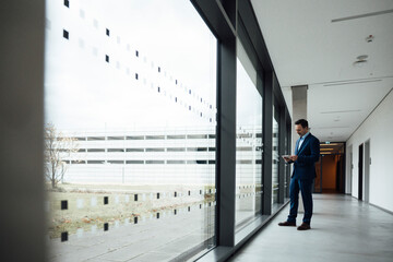 Businessman using tablet PC in office corridor