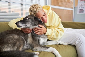 Woman embracing dog on sofa in clinic