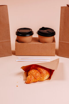 Croissant near coffee cups against beige background
