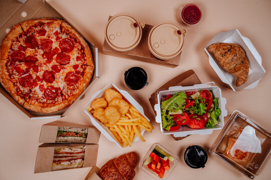 Fast foods and salad with pizza against beige background