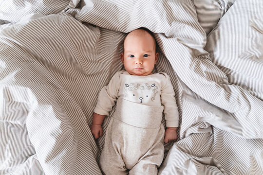 Boy lying over striped sheet on bed at home