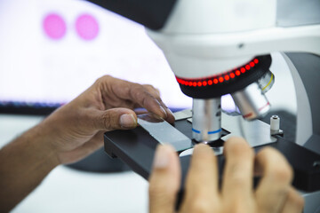 Scientist positioning microscope slide for examining samples at laboratory