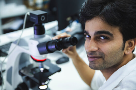 Smiling scientist near microscope at laboratory