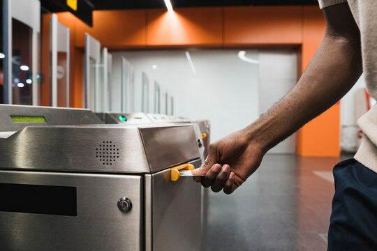 Hand of man inserting metro ticket in electronic barrier