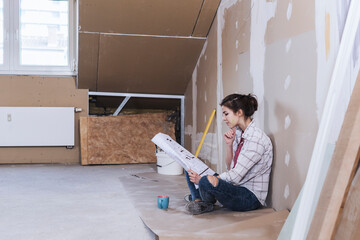 Young woman reading blueprint for home development