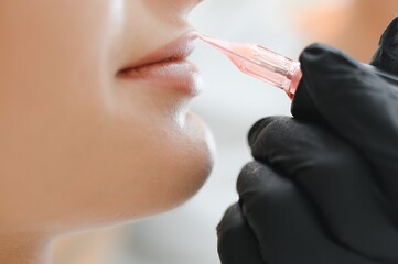 Young woman having permanent makeup on lips in beautician salon