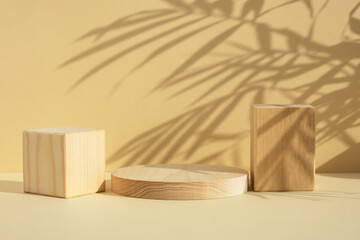 Wooden scenes of different geometric shapes with a shadow of tropical palm leaves on a beige...