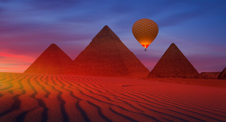 Hot air balloon flying over Giza Pyramid Complex at sunset - Cairo, Egypt