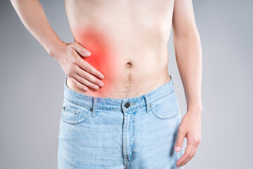 Inflammation of appendicitis, stomach ulcer, man with abdominal pain on a gray background, symptoms of gastritis, diseases of the digestive system - obrazy, fototapety, plakaty