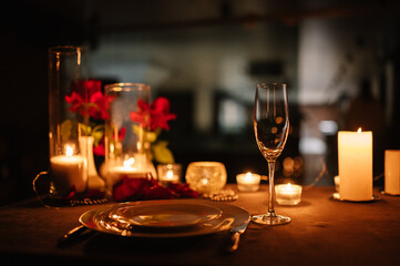 Candlelight date in restaurant. Champagne glasses, bouquet flowers. Romantic dinner setup at night. Table setting for couple, Valentine's Day evening, burning candles for surprise marriage proposal.
