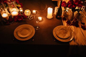 Champagne glasses, flowers. Table setting for couple, Valentine's Day evening, burning candles for...