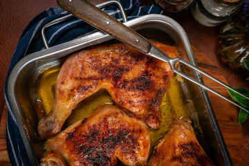 Baked chicken legs in metal baking dish.