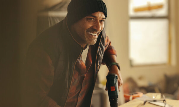 Man performing DIY carpentry work home renovation woodwork with drill gun in kitchen