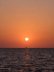 Segelboot am Horizont bei Sonnenuntergang über dem Meer
