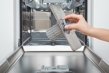 Young adult woman hand holding clean filter for dishwasher. Closeup. Front view.