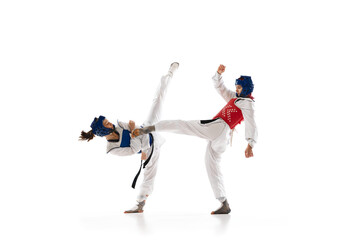 Leg kick. Young girl, competitive taekwondo athletes in dobok and helmet training isolated over white background. Concept of martial arts, combat sport, competition, action