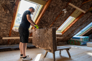 Craftsman cuts insulation material to insulate the attic.