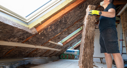 Craftsman holds insulation material to insulate the attic.