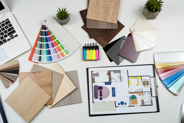 Interior designer's working table with laptop tools wooden color sampler and blueprints of the...