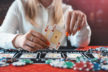 closeup of female hand with poker ships and play card at casino