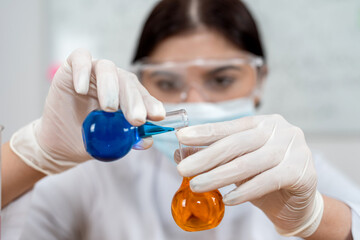 Young woman laboratory technician mixed flask with liquid, research in clinical laboratory