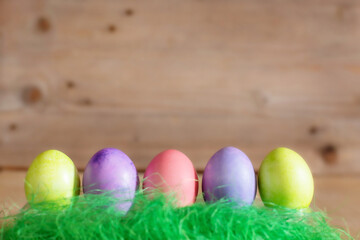 Row of colorful Easter eggs on wooden background copy space