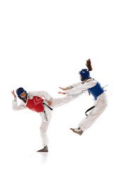 Full-length dynamic image of young girls in white dobok practicing, raining taekwondo isolated over white background. Concept of martial arts, combat sport, competition, action