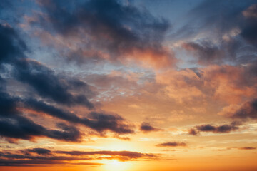 A vibrant sunset sky with a captivating array of orange hues painting a dramatic cloudscape,...