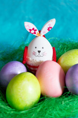 Colorful Easter eggs and bunny rabbit in green next decoration on blue background