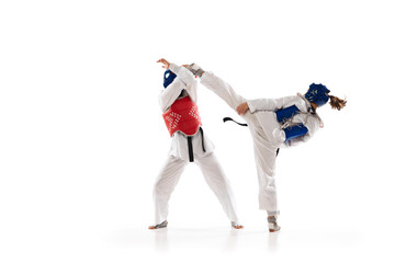 Kick and protection stunts. Young girls, taekwondo athletes in motion, practicing isolated over white background. Concept of martial arts, combat sport, competition, action, school