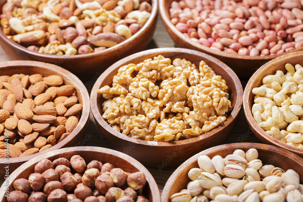 Poster bowls of various mixed nuts on wooden background