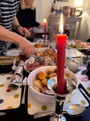 Vertical cropped shot of a red candle burning on christmas dinner table