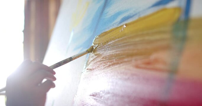 Close up of senior biracial woman painting on big canvas at home, slow motion